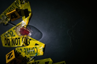 Flat lay composition with evidences and crime scene tape on black slate background, space for text Photo of Flat lay composition with evidences and crime scene tape on black slate background, space for text