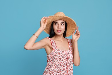 Beautiful young woman with straw hat on light blue background Photo of Beautiful young woman with straw hat on light blue background