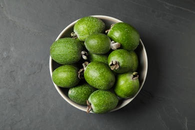 Fresh green feijoa fruits in bowl on black table, top view Photo of Fresh green feijoa fruits in bowl on black table, top view