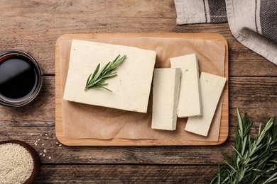 Delicious tofu with rosemary served on wooden table, flat lay Photo of Delicious tofu with rosemary served on wooden table, flat lay