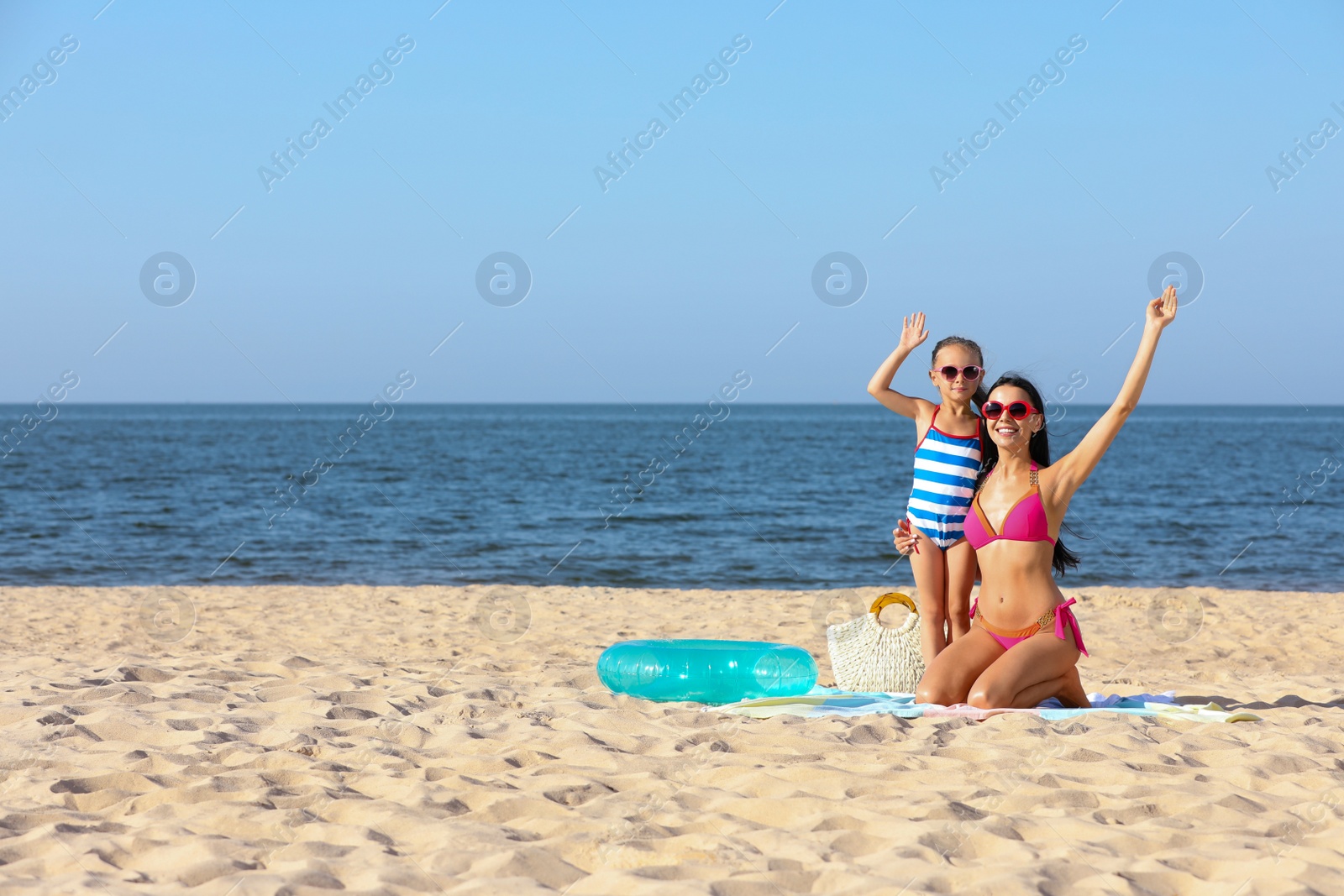 Happy mother and daughter on sandy beach near sea, space for text. Summer holidays with family Photo of Happy mother and daughter on sandy beach near sea, space for text. Summer holidays with family
