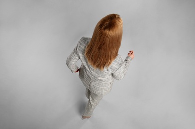Young woman on grey background, back view Photo of Young woman on grey background, back view