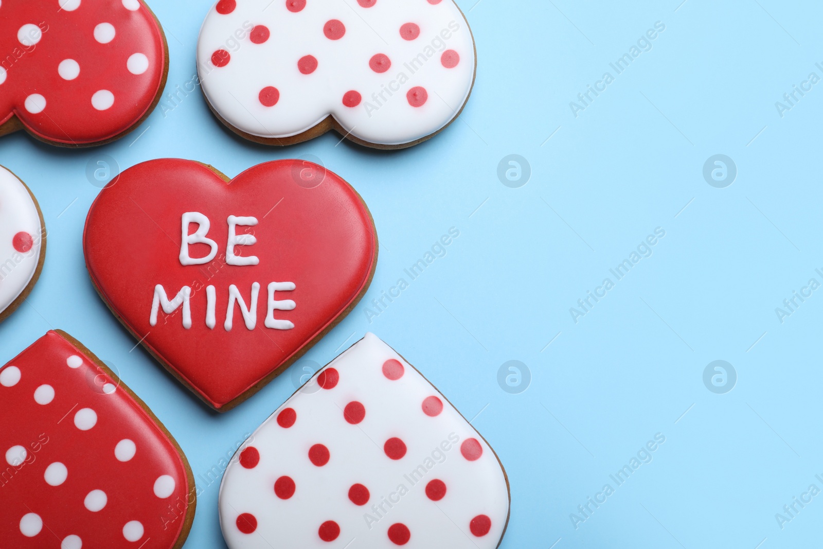 Photo of Delicious heart shaped cookies on light blue background, flat lay with space for text. Valentine's Day