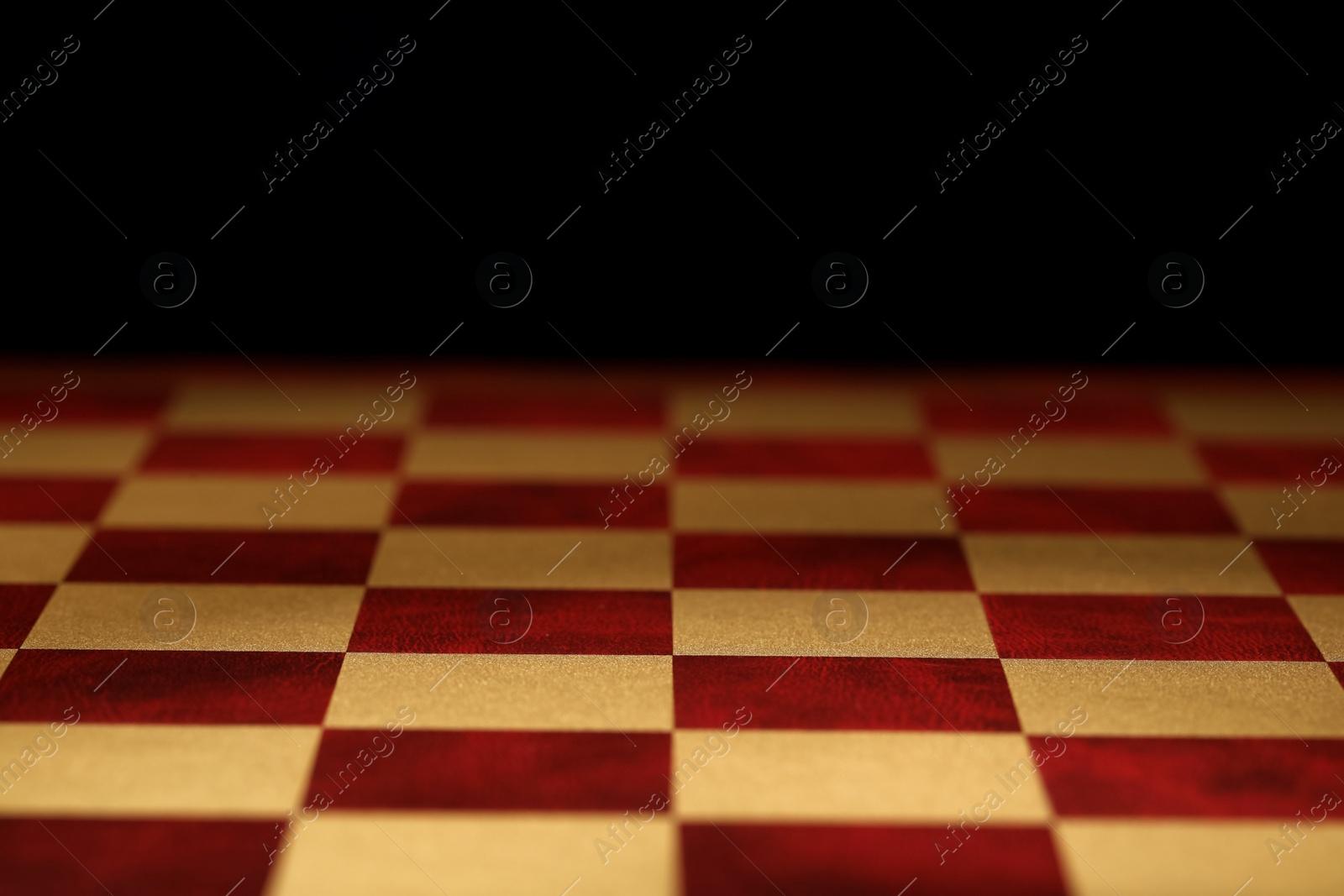 Checkered chessboard on dark background, closeup view Photo of Checkered chessboard on dark background, closeup view