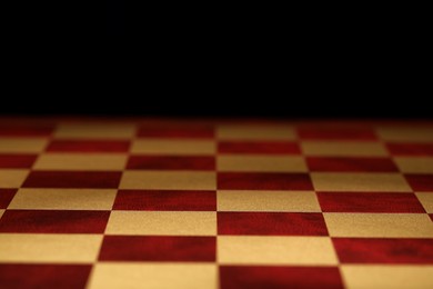 Checkered chessboard on dark background, closeup view Photo of Checkered chessboard on dark background, closeup view