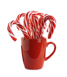 Red cup with sweet Christmas candy canes isolated on white Photo of Red cup with sweet Christmas candy canes isolated on white