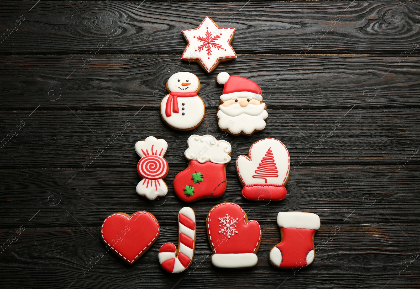 Christmas tree shape made of delicious decorated gingerbread cookies on black wooden table, flat lay Photo of Christmas tree shape made of delicious decorated gingerbread cookies on black wooden table, flat lay