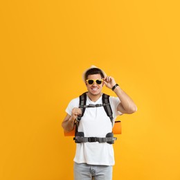 Male tourist with travel backpack on yellow background Photo of Male tourist with travel backpack on yellow background
