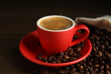 Photo of Cup of tasty coffee and beans on wooden table
