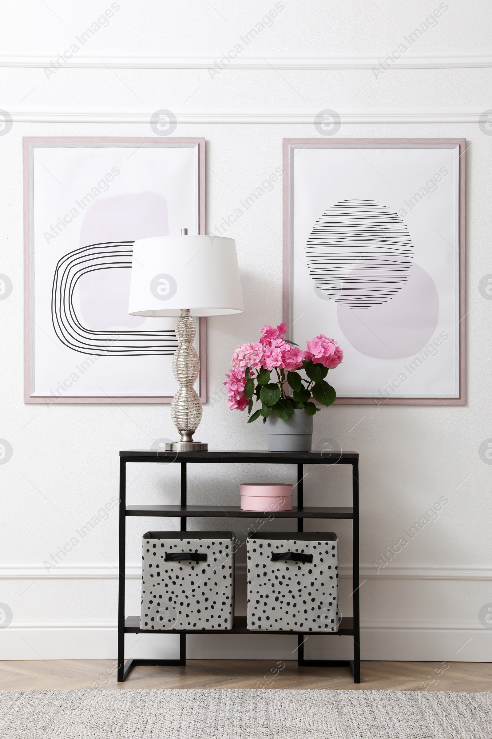 Console table with beautiful hydrangea flower and lamp near white wall in hallway. Interior design Photo of Console table with beautiful hydrangea flower and lamp near white wall in hallway. Interior design