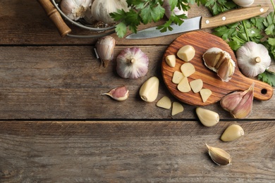 Flat lay composition with fresh sliced and whole garlic on wooden table, space for text. Organic product Photo of Flat lay composition with fresh sliced and whole garlic on wooden table, space for text. Organic product