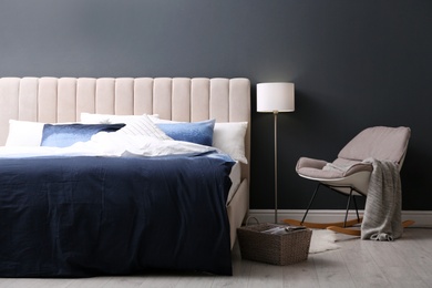 Comfortable bed with pillows and soft blanket in room. Stylish interior design Photo of Comfortable bed with pillows and soft blanket in room. Stylish interior design