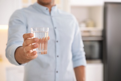 Man holding glass of pure water in kitchen, closeup Photo of Man holding glass of pure water in kitchen, closeup