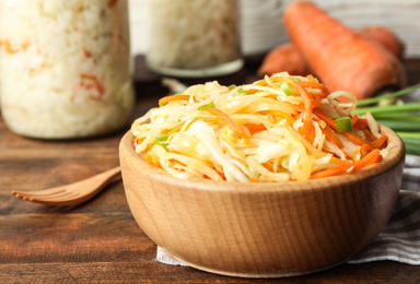 Photo of Tasty fermented cabbage on wooden table, closeup