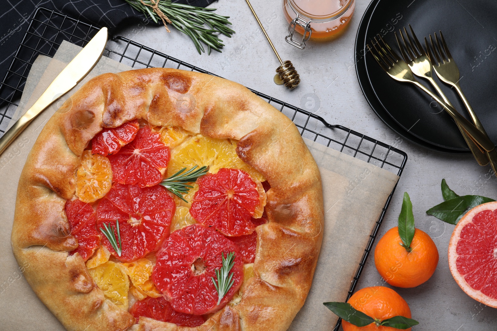 Tasty galette with citrus fruits and rosemary served on grey table, flat lay Photo of Tasty galette with citrus fruits and rosemary served on grey table, flat lay