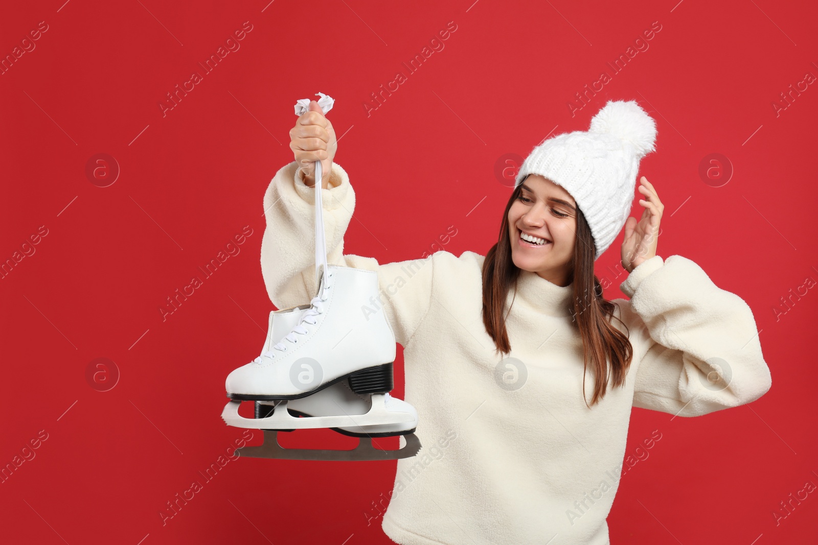 Happy woman with ice skates on red background Photo of Happy woman with ice skates on red background
