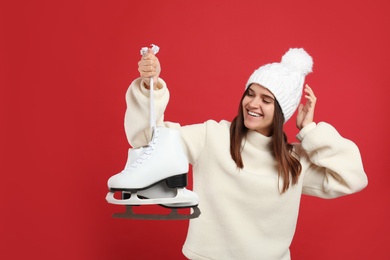 Happy woman with ice skates on red background Photo of Happy woman with ice skates on red background