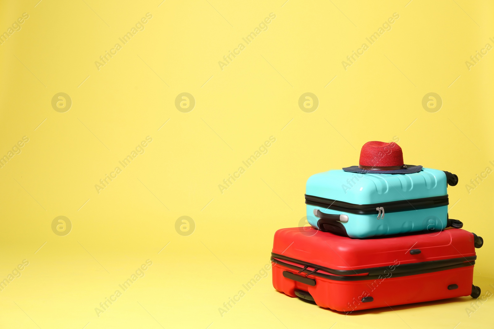 Stylish suitcases with hat on yellow background. Space for text Photo of Stylish suitcases with hat on yellow background. Space for text