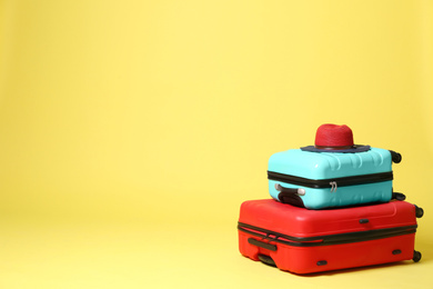 Photo of Stylish suitcases with hat on yellow background. Space for text