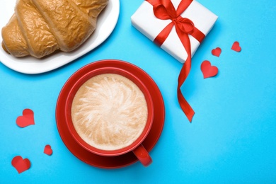 Cup of coffee, croissant and gift box on turquoise background, flat lay. Valentine's day breakfast Photo of Cup of coffee, croissant and gift box on turquoise background, flat lay. Valentine's day breakfast