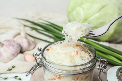 Fork with tasty fermented cabbage over jar, closeup Photo of Fork with tasty fermented cabbage over jar, closeup