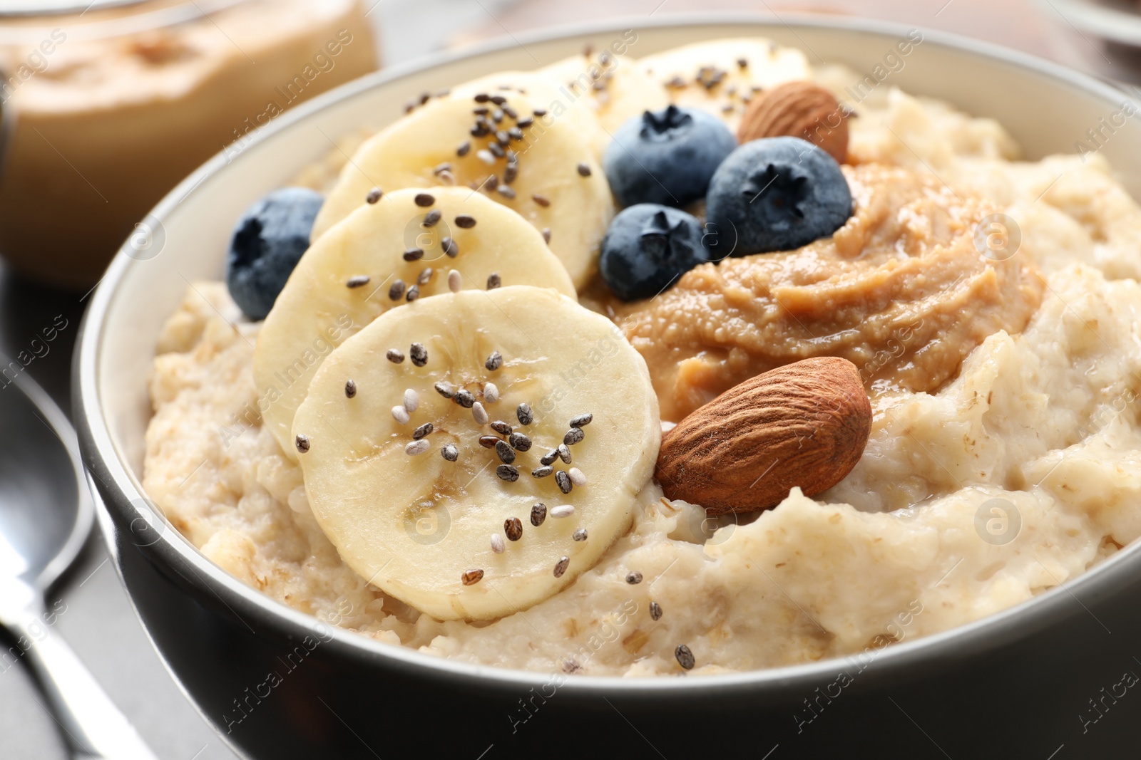 Tasty oatmeal porridge with toppings in bowl on table, closeup Photo of Tasty oatmeal porridge with toppings in bowl on table, closeup
