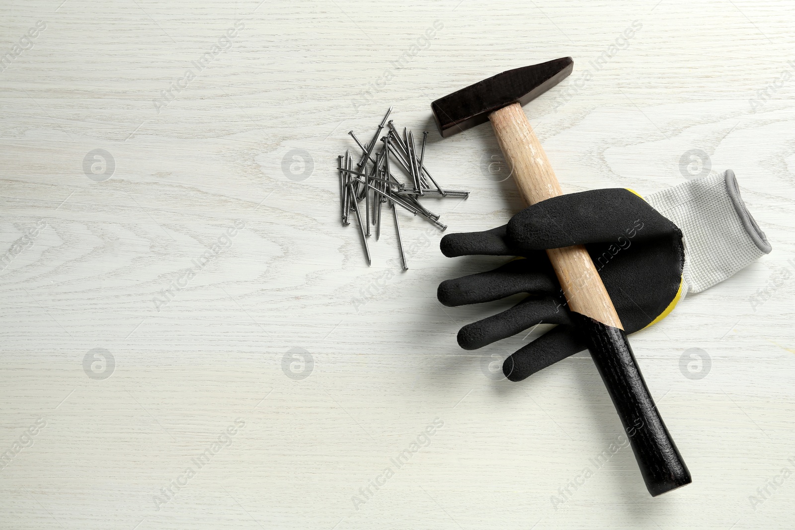 Hammer, glove and metal nails on white wooden table, flat lay. Space for text Photo of Hammer, glove and metal nails on white wooden table, flat lay. Space for text