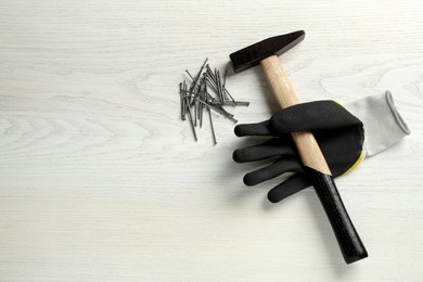 Hammer, glove and metal nails on white wooden table, flat lay. Space for text Photo of Hammer, glove and metal nails on white wooden table, flat lay. Space for text