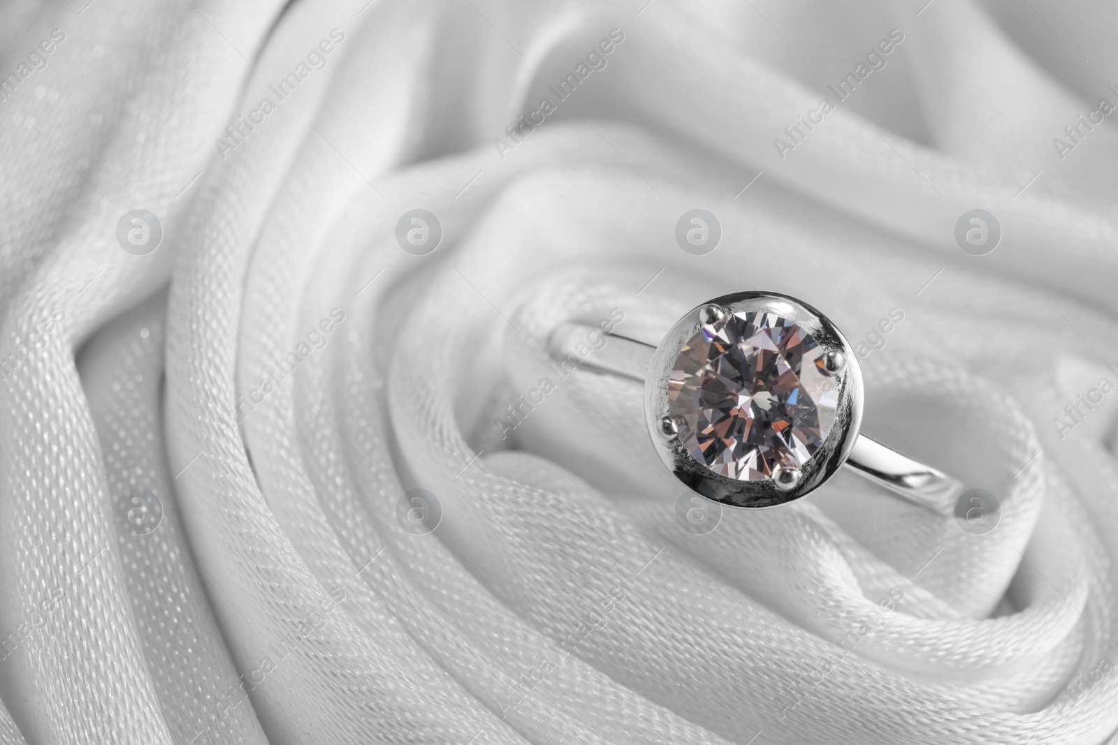 Beautiful engagement ring in white fabric, closeup view. Space for text Photo of Beautiful engagement ring in white fabric, closeup view. Space for text