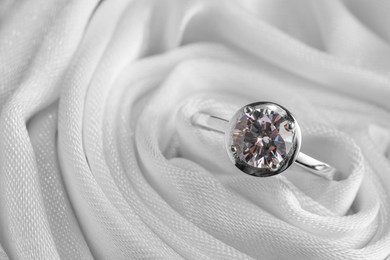 Beautiful engagement ring in white fabric, closeup view. Space for text Photo of Beautiful engagement ring in white fabric, closeup view. Space for text