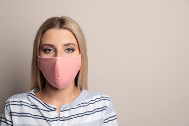 Young woman in protective face mask on beige background. Space for text Photo of Young woman in protective face mask on beige background. Space for text