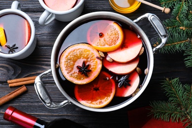 Delicious mulled wine and ingredients on black wooden table, flat lay Photo of Delicious mulled wine and ingredients on black wooden table, flat lay