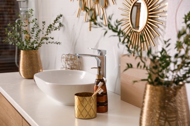 Vase with beautiful branches and toiletries near vessel sink in bathroom. Interior design Photo of Vase with beautiful branches and toiletries near vessel sink in bathroom. Interior design