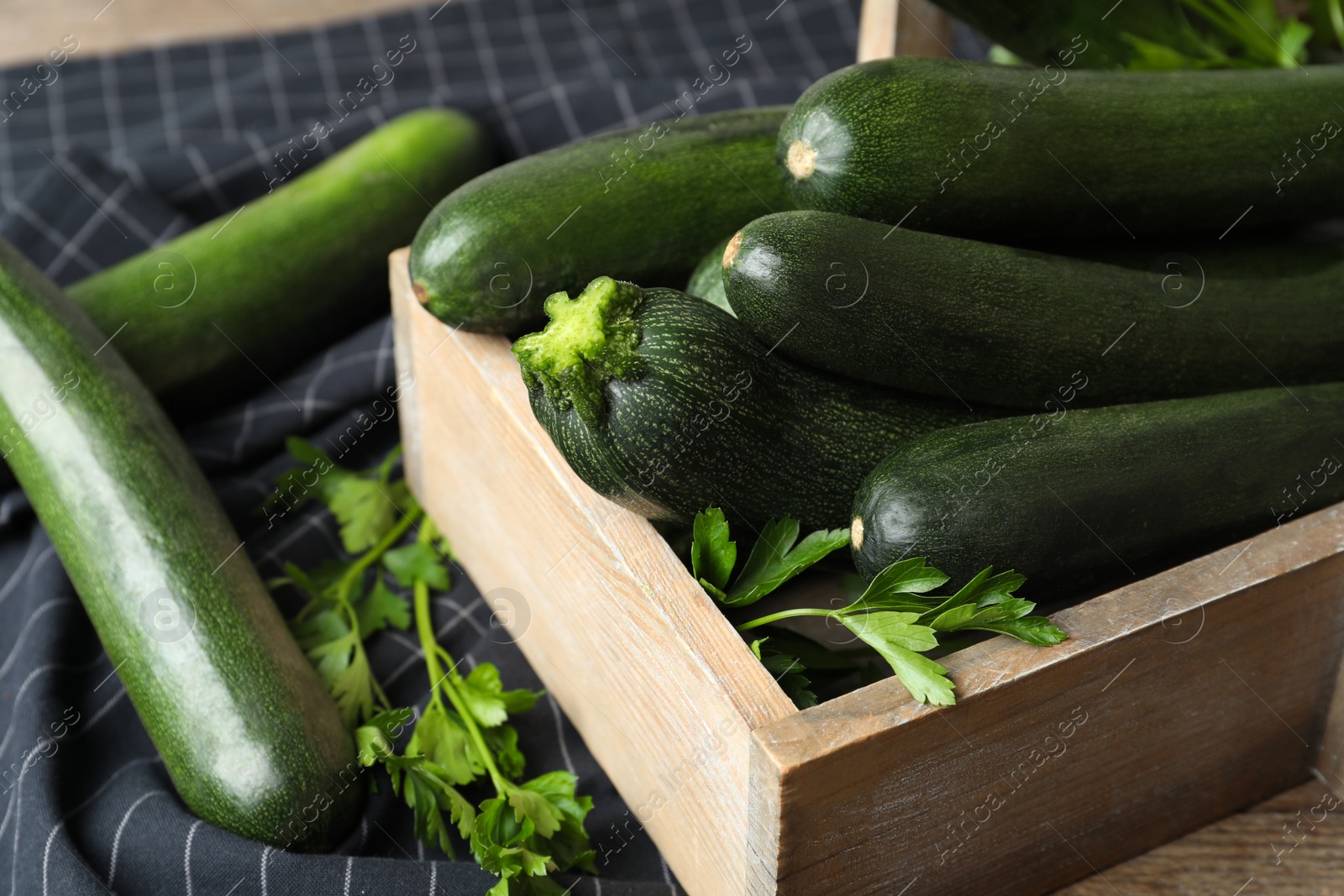 Crate with green zucchinis and parsley on table, closeup Photo of Crate with green zucchinis and parsley on table, closeup