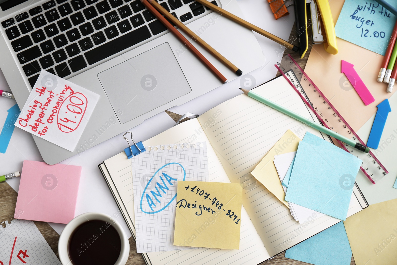 Photo of Laptop, notes and office stationery in mess on desk, top view. Overwhelmed with work