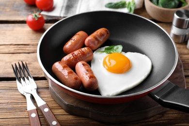 Romantic breakfast with fried sausages and heart shaped egg on wooden table. Valentine's day celebration Photo of Romantic breakfast with fried sausages and heart shaped egg on wooden table. Valentine's day celebration