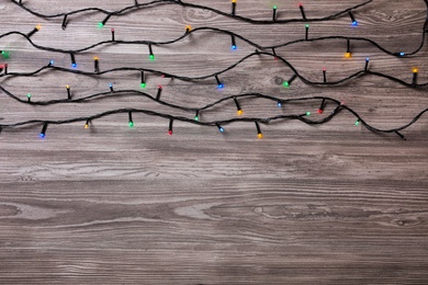 Christmas lights on wooden table, top view. Space for text Photo of Christmas lights on wooden table, top view. Space for text