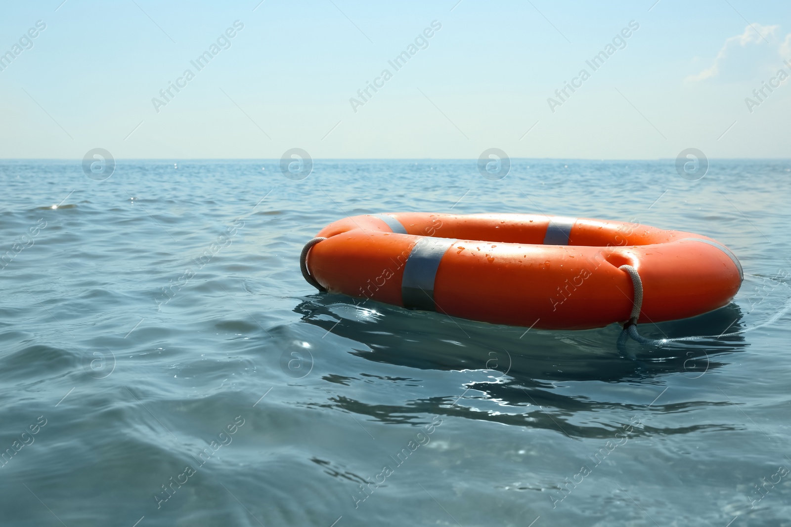 Orange life buoy floating in sea. Emergency rescue equipment Photo of Orange life buoy floating in sea. Emergency rescue equipment