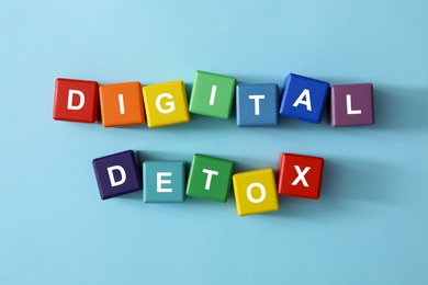 Colorful cubes with phrase DIGITAL DETOX on light blue background, flat lay Photo of Colorful cubes with phrase DIGITAL DETOX on light blue background, flat lay