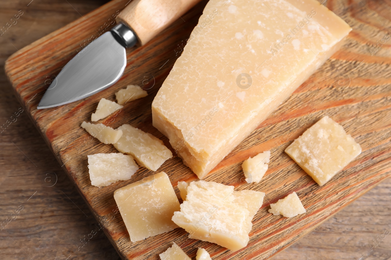 Parmesan cheese with knife on wooden table, top view Photo of Parmesan cheese with knife on wooden table, top view