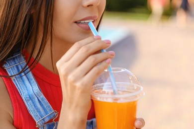 Young woman drinking tasty juice outdoors, closeup Image of Young woman drinking tasty juice outdoors, closeup