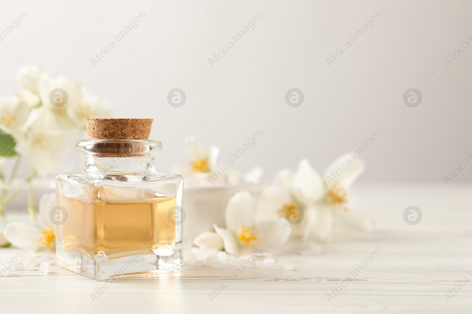 Beautiful composition with jasmine essential oil and fresh flowers on white wooden table. Space for text Photo of Beautiful composition with jasmine essential oil and fresh flowers on white wooden table. Space for text