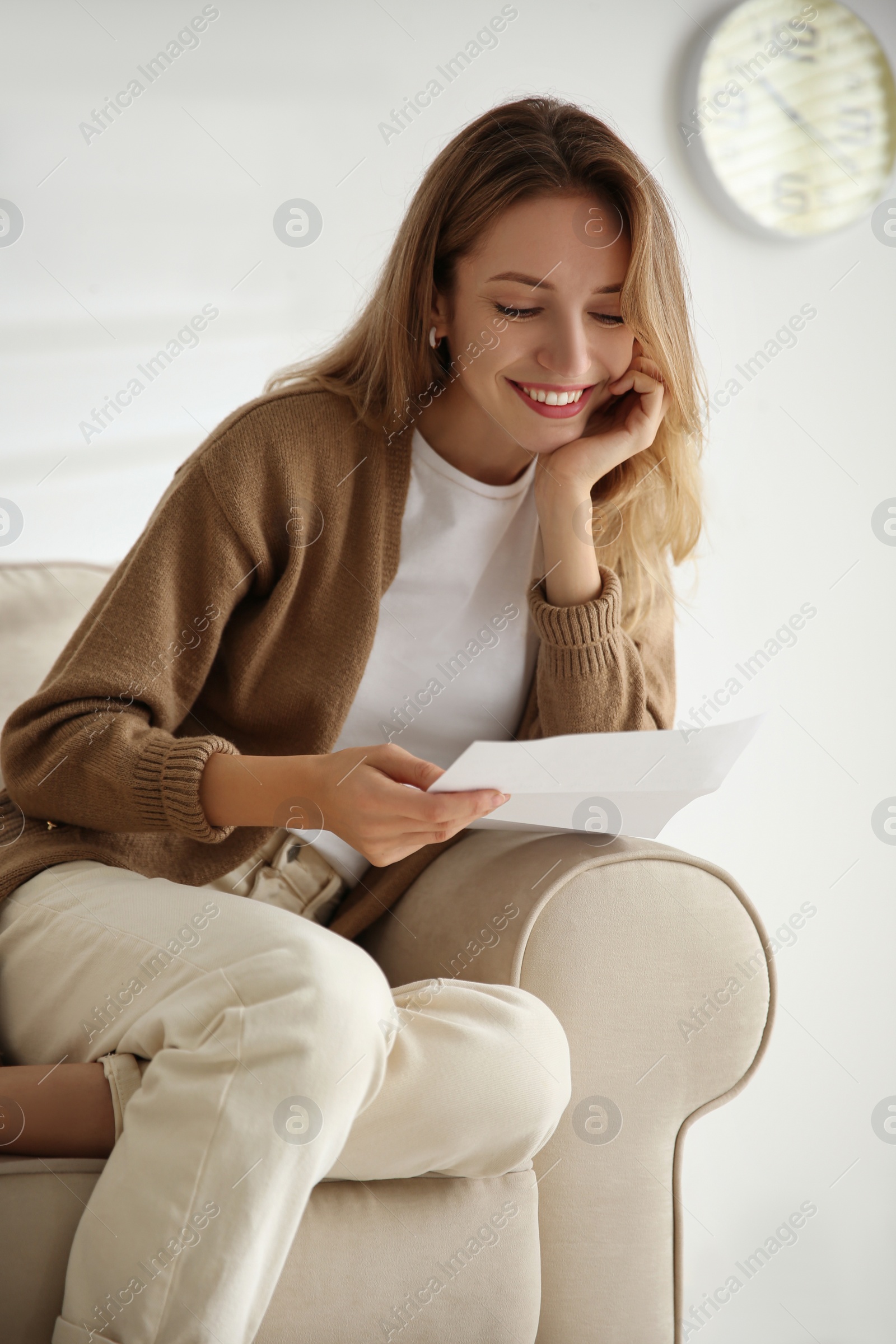 Happy woman reading letter on sofa at home Photo of Happy woman reading letter on sofa at home