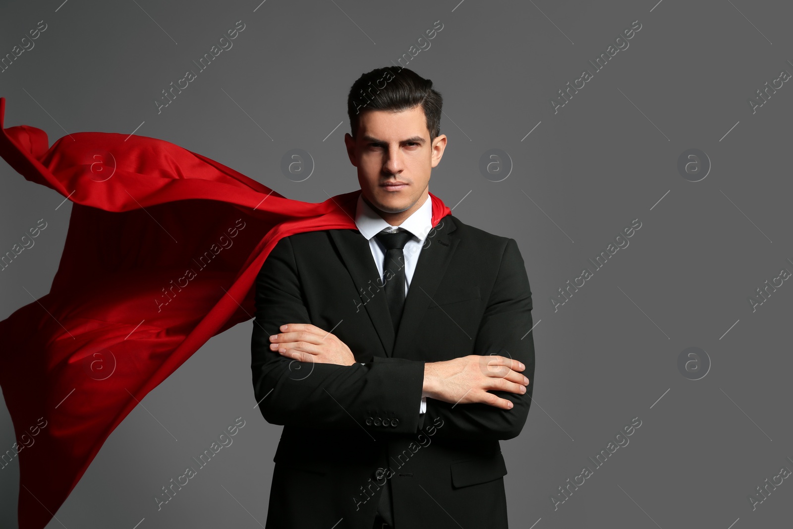 Businessman wearing superhero cape on grey background Photo of Businessman wearing superhero cape on grey background