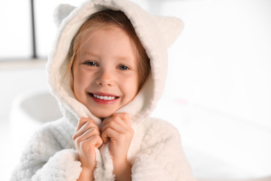 Photo of Cute little girl in bathroom. Space for text