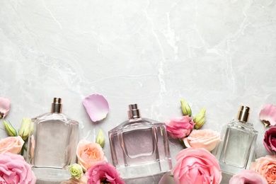 Flat lay composition of different perfume bottles and flowers on light grey marble background, space for text Photo of Flat lay composition of different perfume bottles and flowers on light grey marble background, space for text