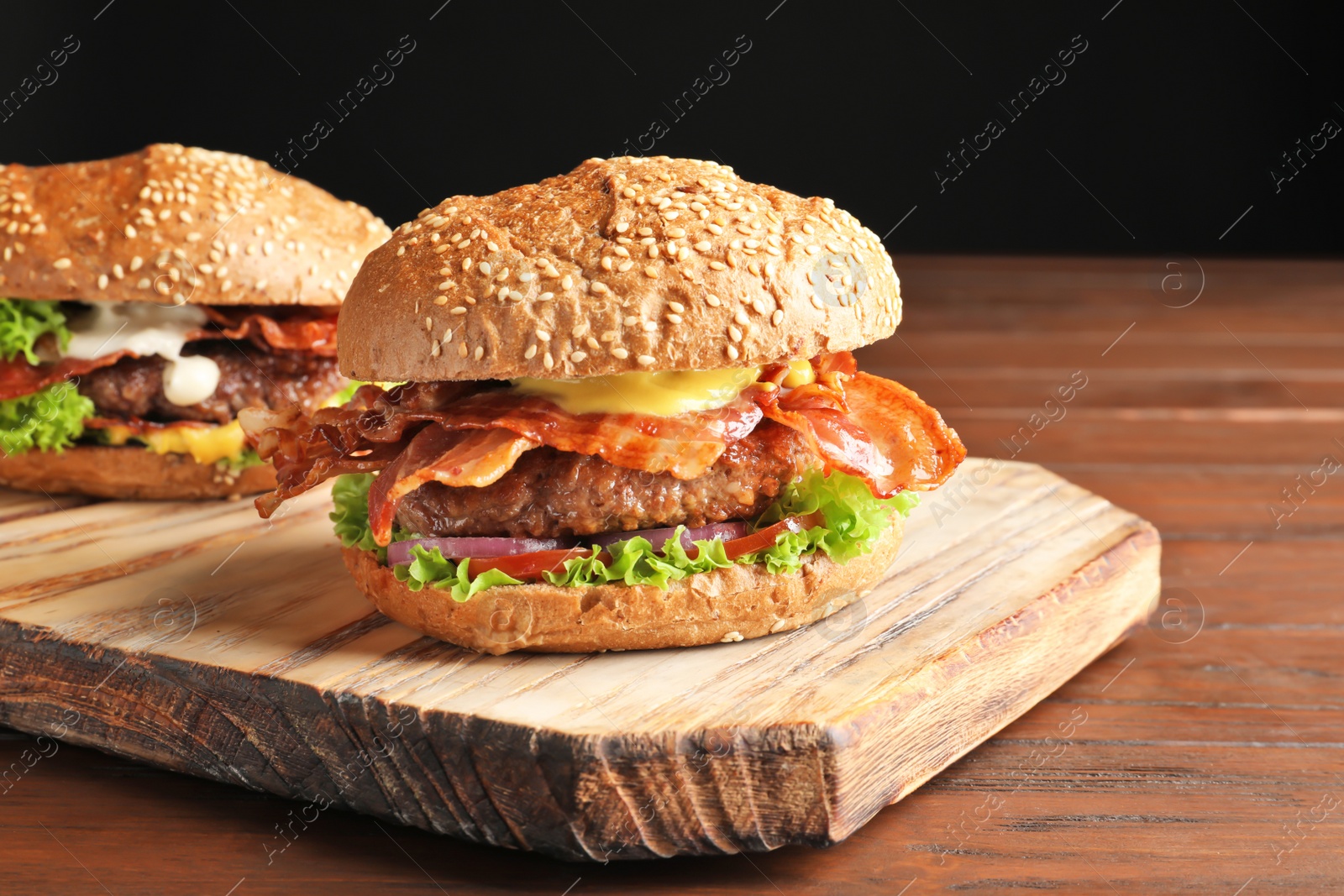 Tasty burgers with bacon on wooden board Photo of Tasty burgers with bacon on wooden board