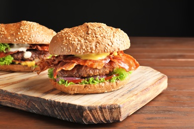 Tasty burgers with bacon on wooden board Photo of Tasty burgers with bacon on wooden board