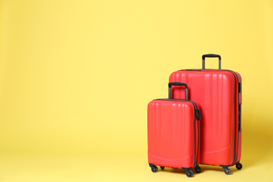 Stylish red suitcases on yellow background. Space for text Photo of Stylish red suitcases on yellow background. Space for text