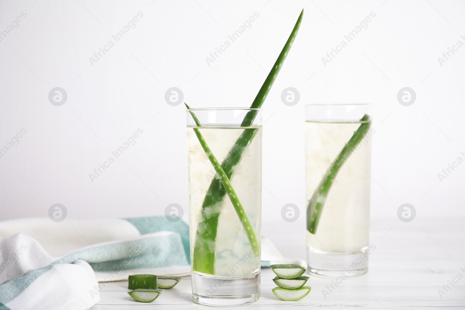 Fresh aloe drink with leaves in glasses on white wooden table Photo of Fresh aloe drink with leaves in glasses on white wooden table